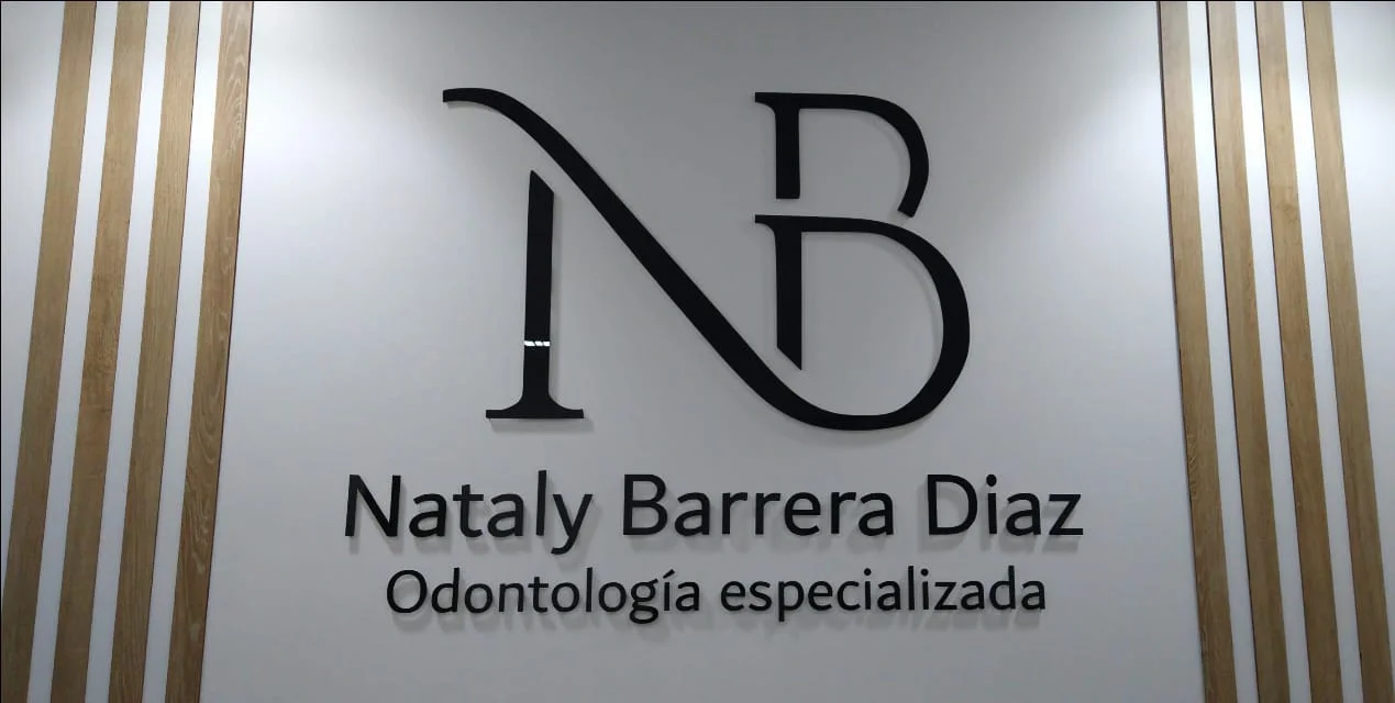 Logotipo NB Nataly Barrera Diaz en acrílico negro 3D sobre muro con listones de madera