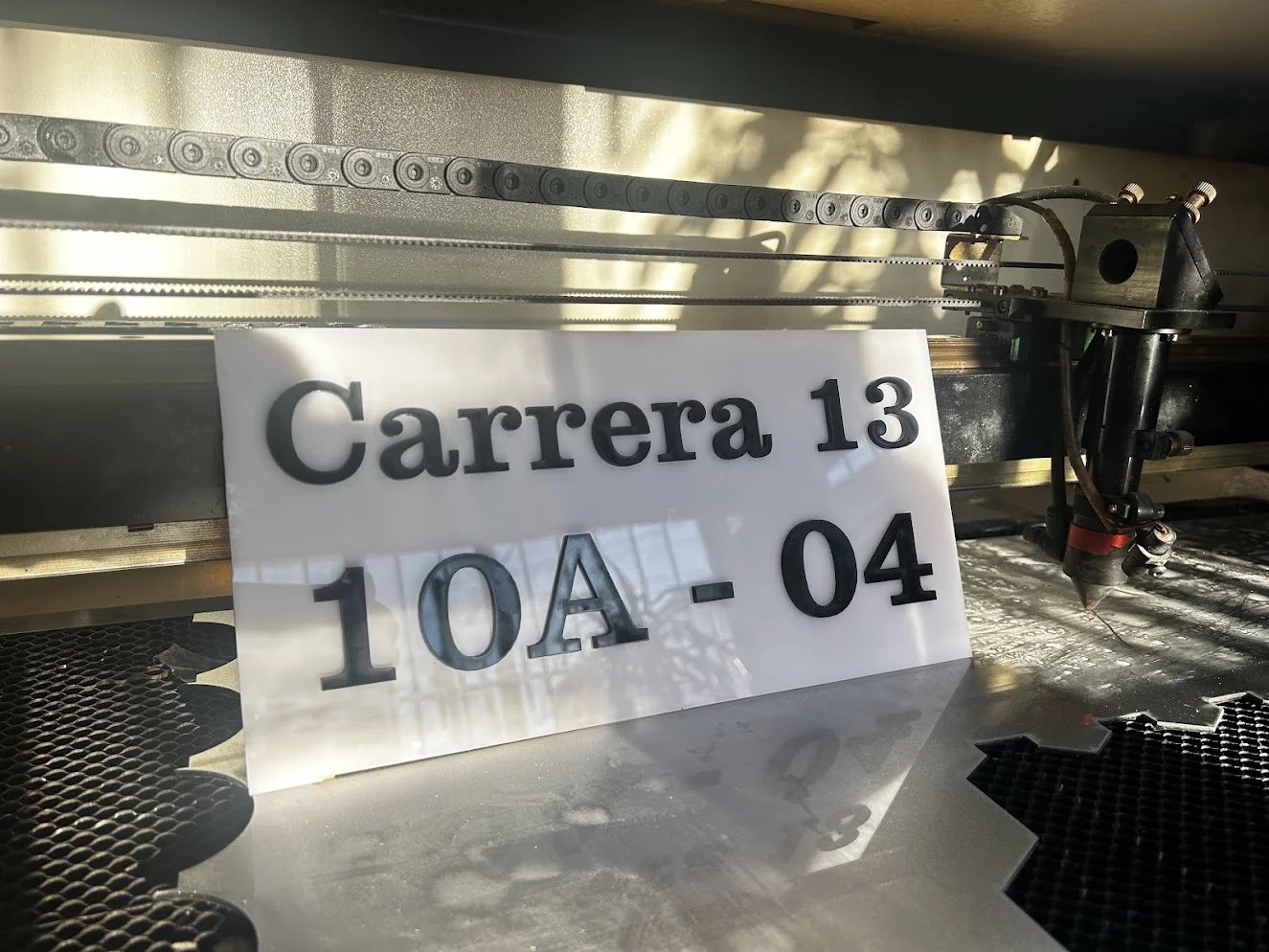 Placa Carrera 13 en acrílico blanco con números en relieve 3D sobre mesa láser